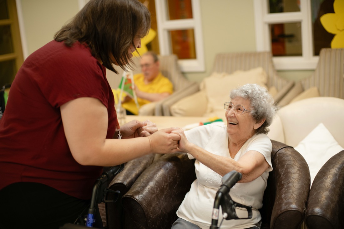 Caregiver holding hands and smiling with a senior at home