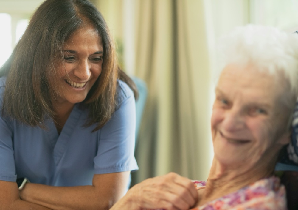 Caregiver smiling warmly with senior patient at home